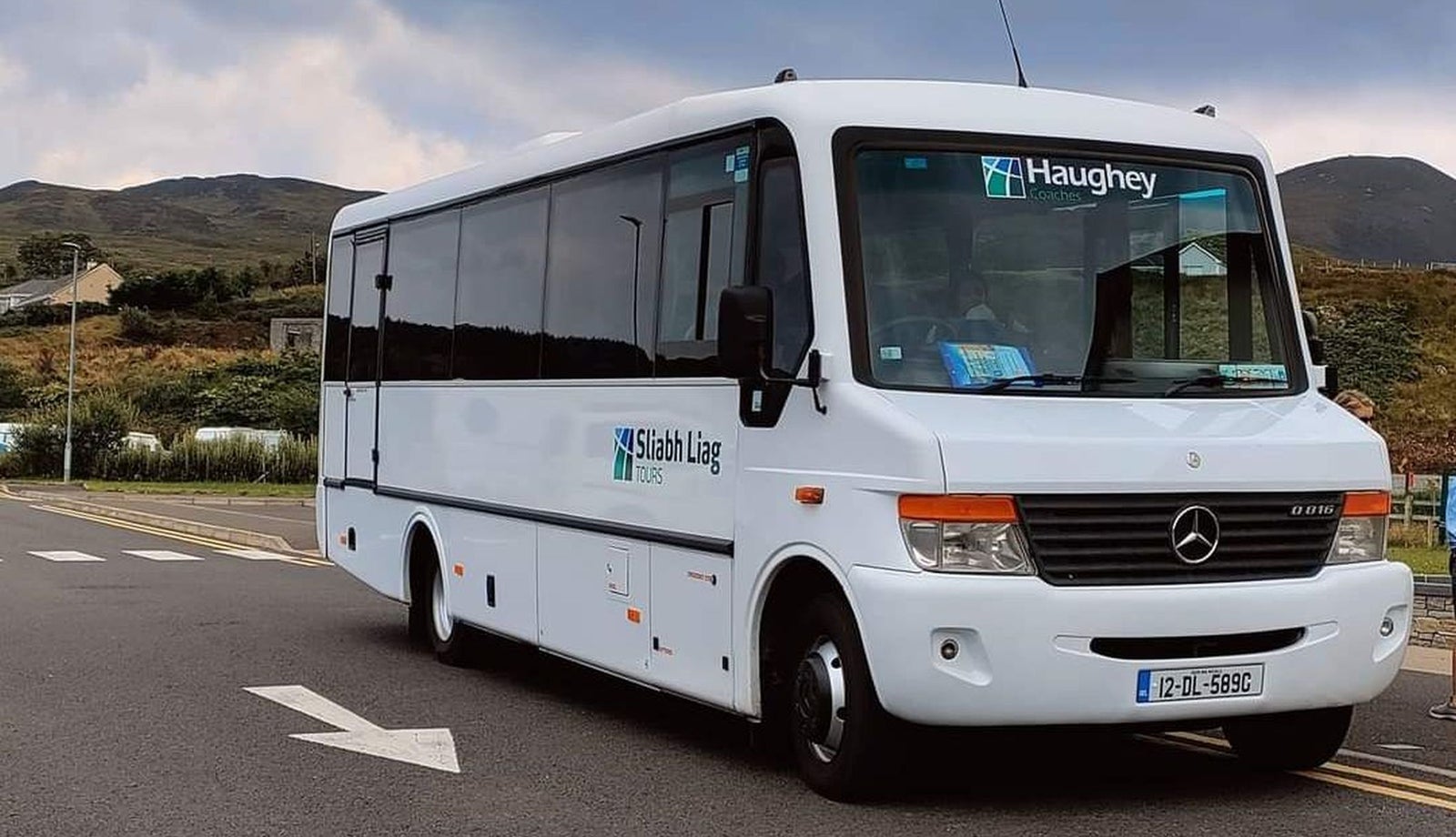 A minibus with a tour company logo parked in a scenic location
