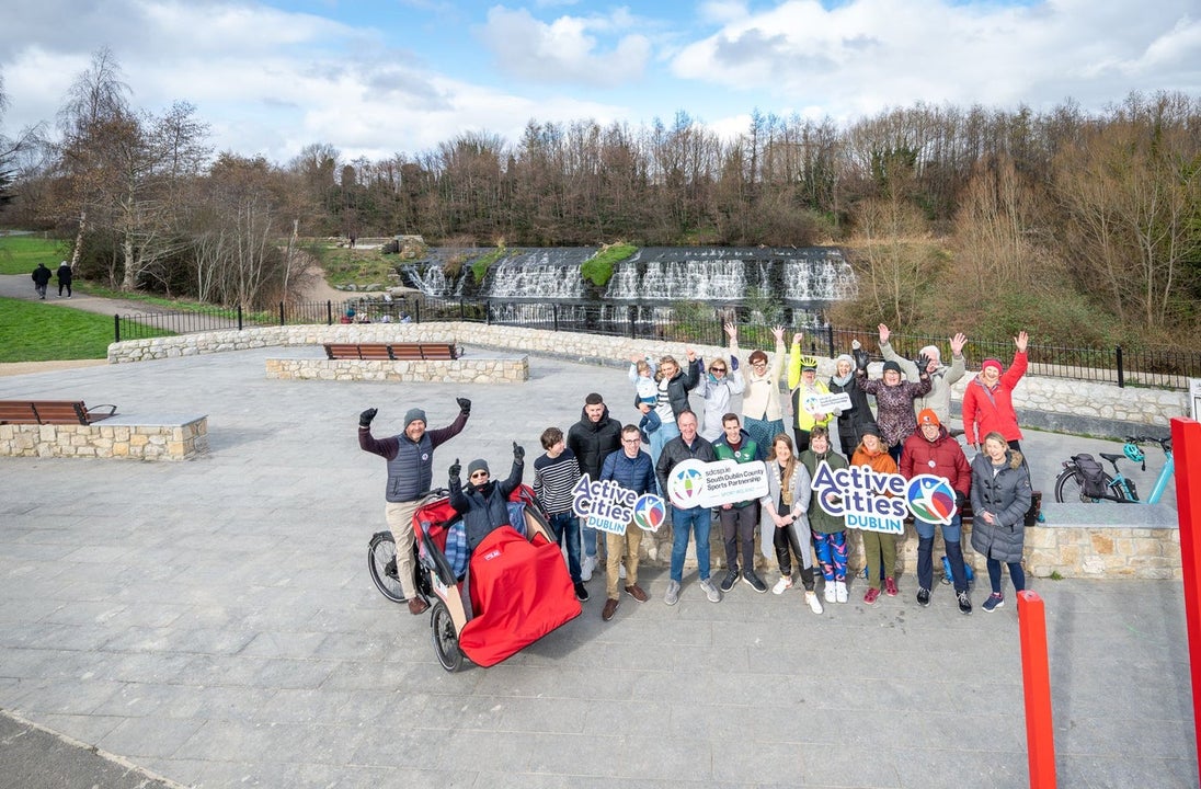 A group of people posing with trishaws and signs promoting cycling