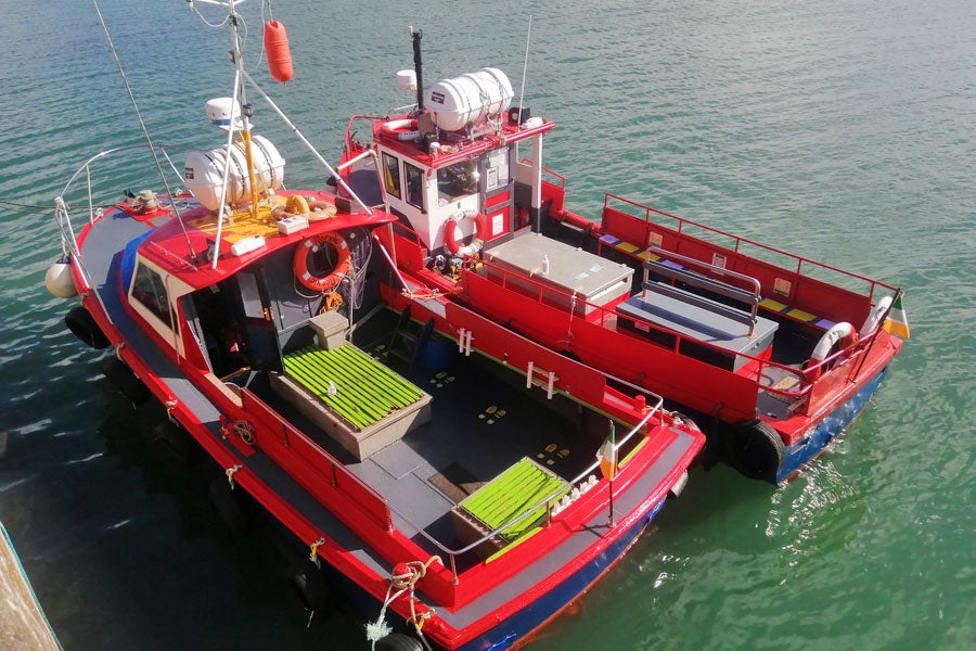 Two small passenger ferries orange in colour tied up at pier
