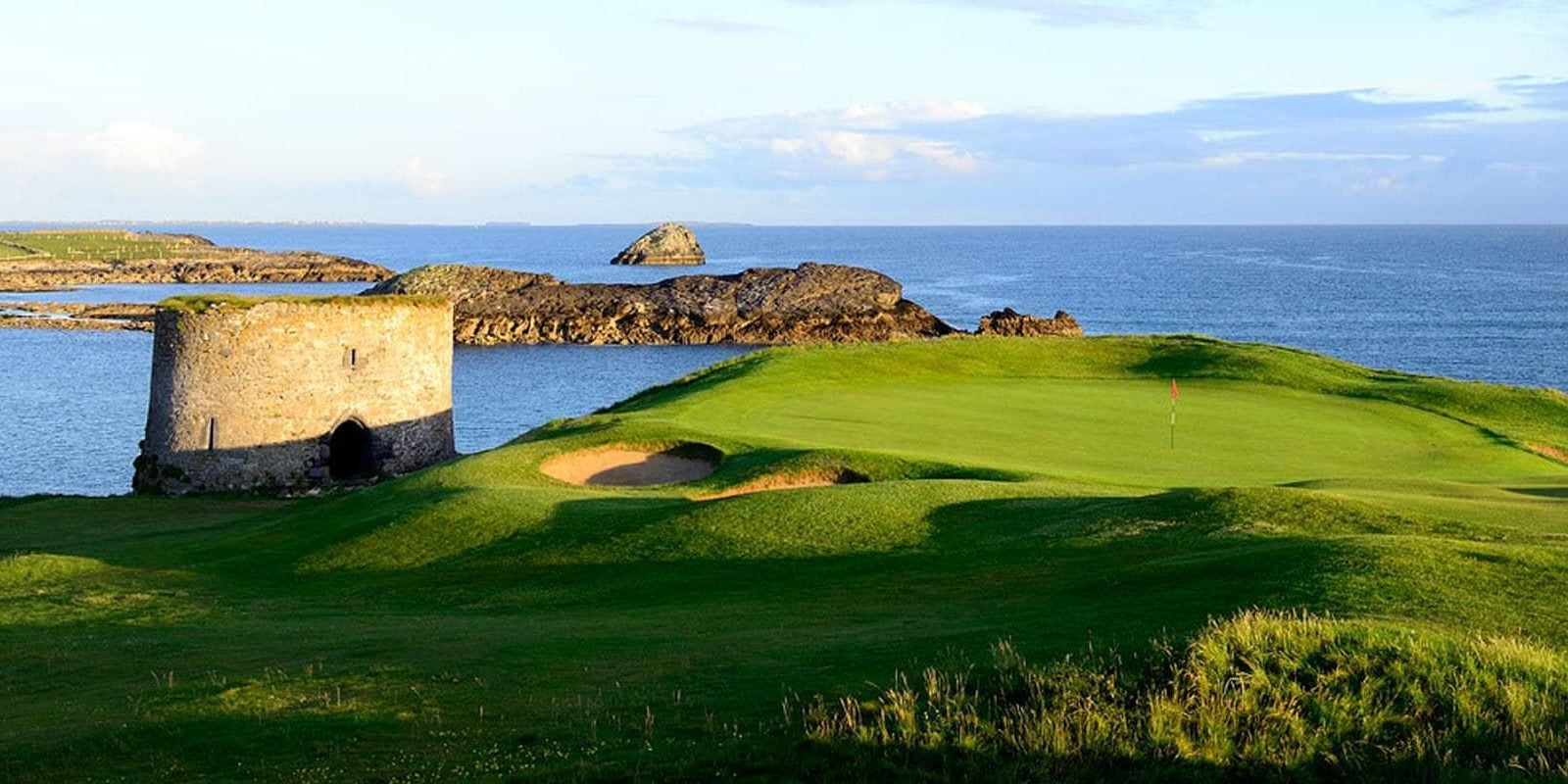 A golf course near the sea with a round tower
