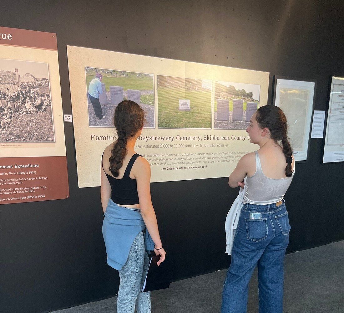 Two people reading information off a storyboard set on a black wall