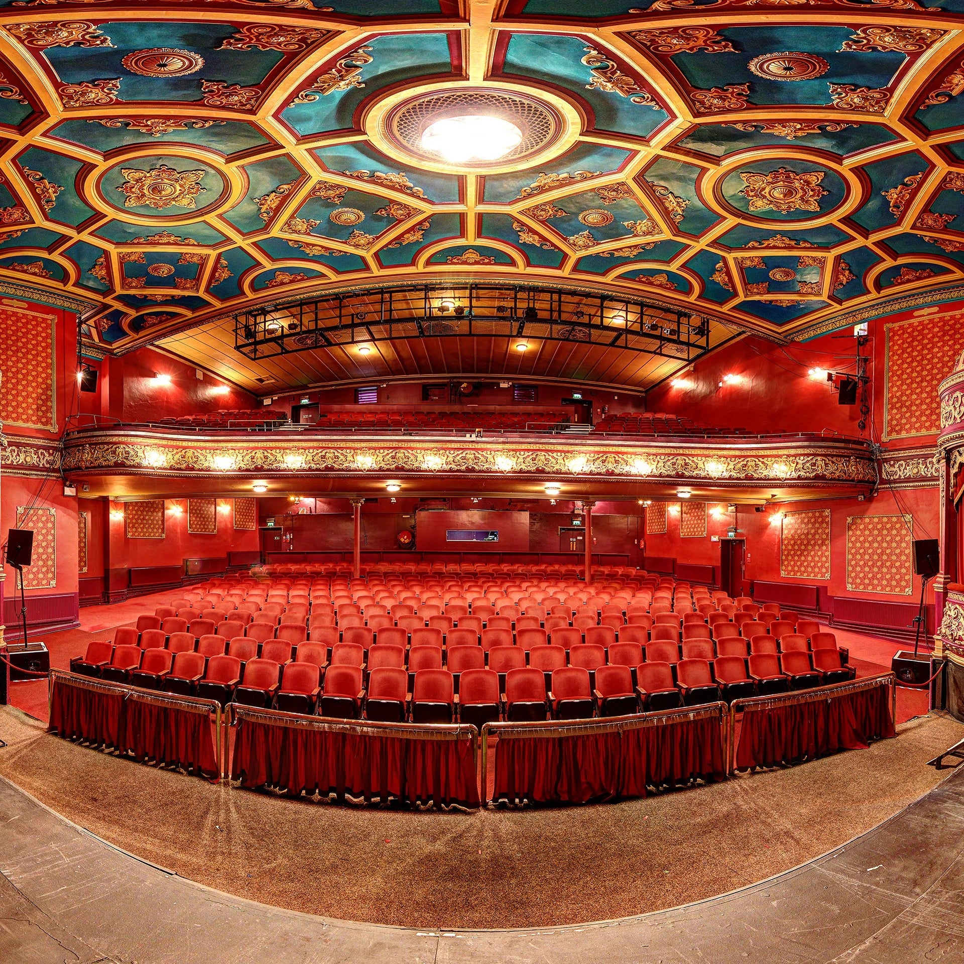 Empty auditorium with rows of red seats and a blue and gold ceiling