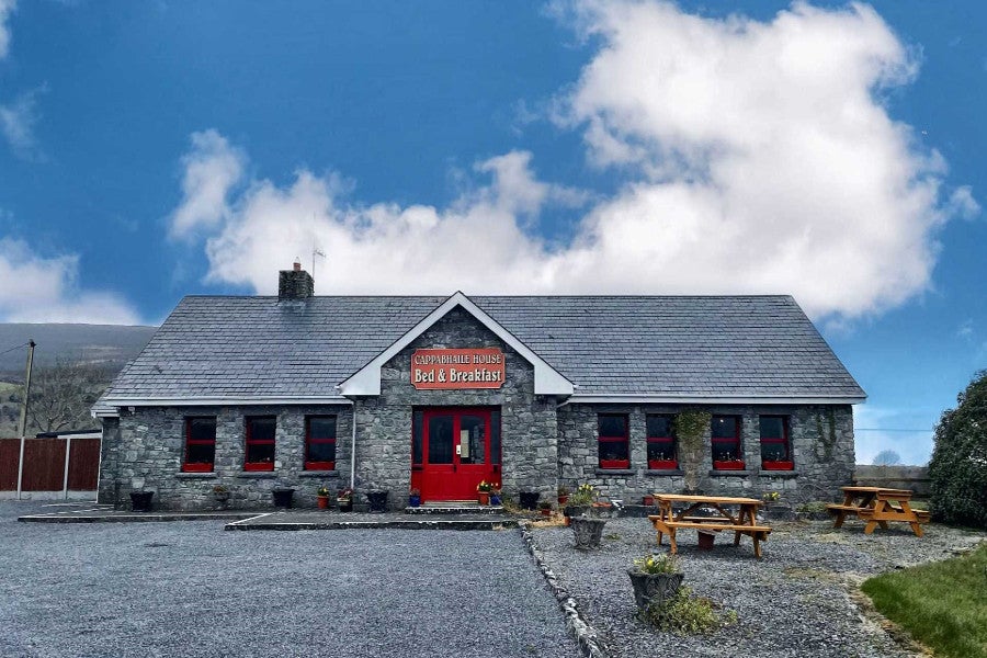 Stone faced house with parking area.