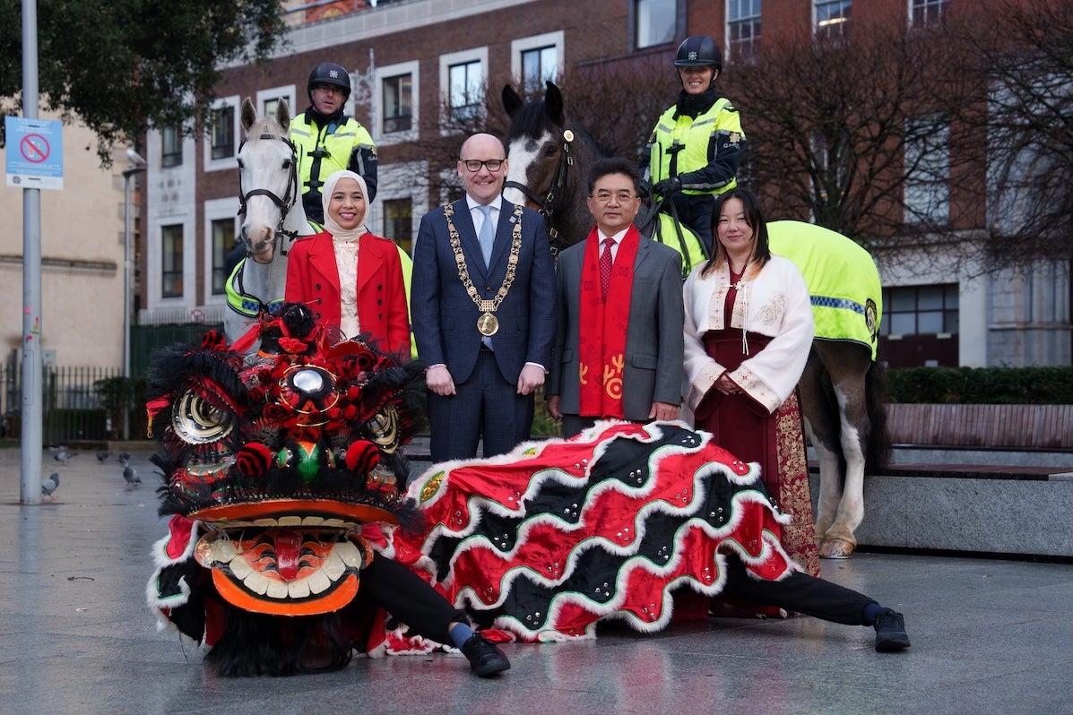 A group of smiling people including 2 on horses and a dragon