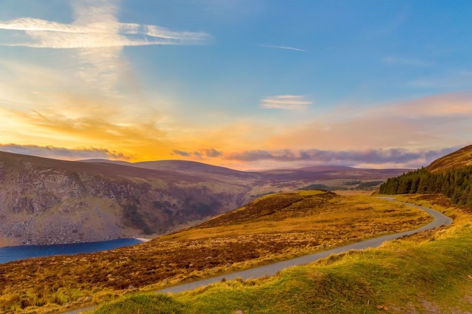 Colourful sky over a scenic landscape with a narrow winding road