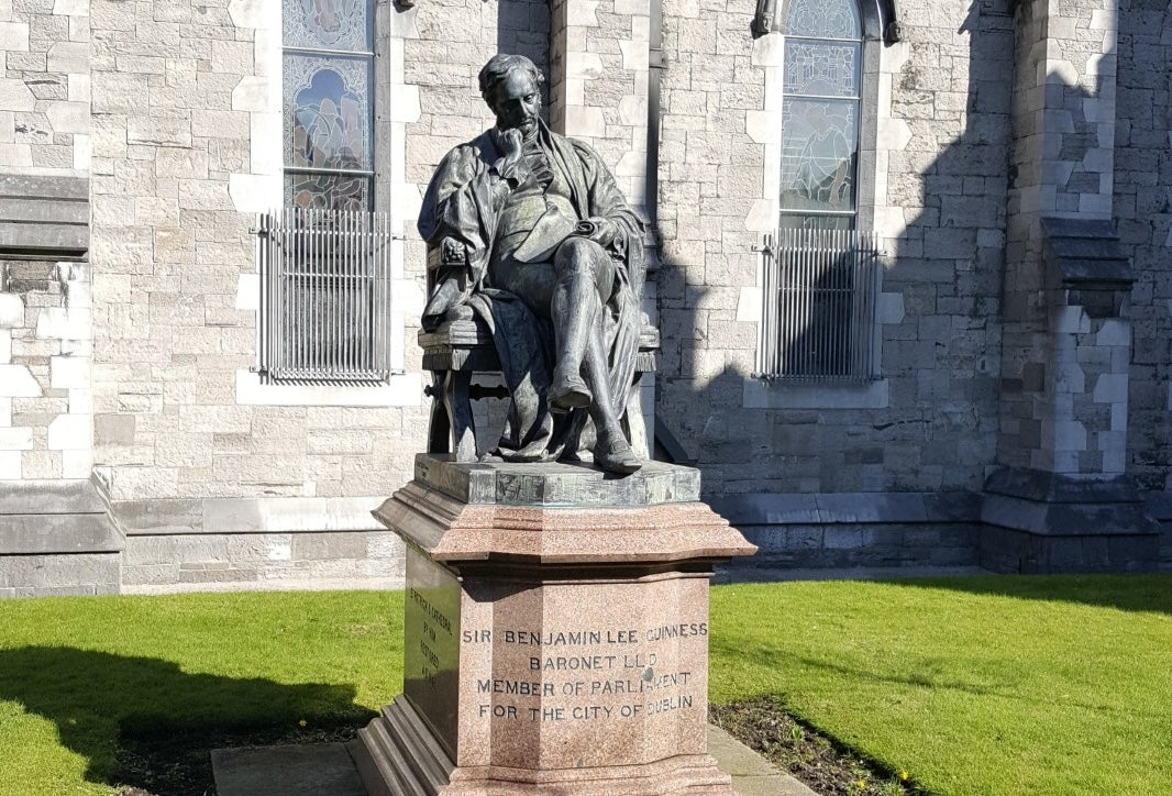 A large statue of a seated man on a plinth with church in the background.