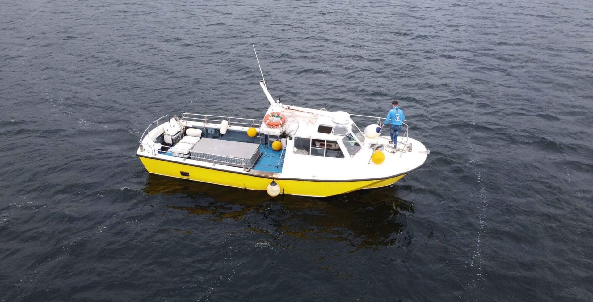 Aerial view of a small white and yellow boat anchored at sea