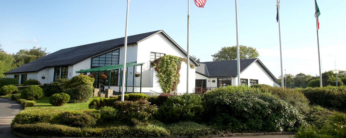 The exterior of Father Peyton Memorial Centre with shrubs and flag poles in front of building