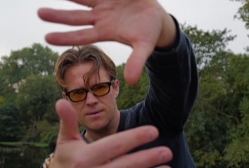 View of man with his hands held up at arms length framing his face.