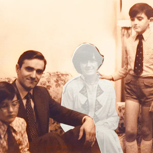 Old sepia colour photo of family on a sofa with the mother figure faded out in grey.