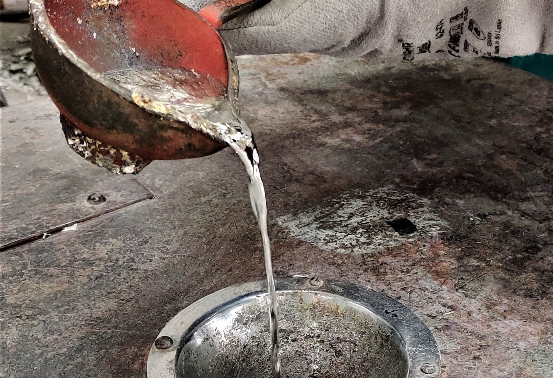 Copper pot pouring melted silver into a silver pot