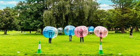 A group of people wearing large plastic bubbles kicking around a football