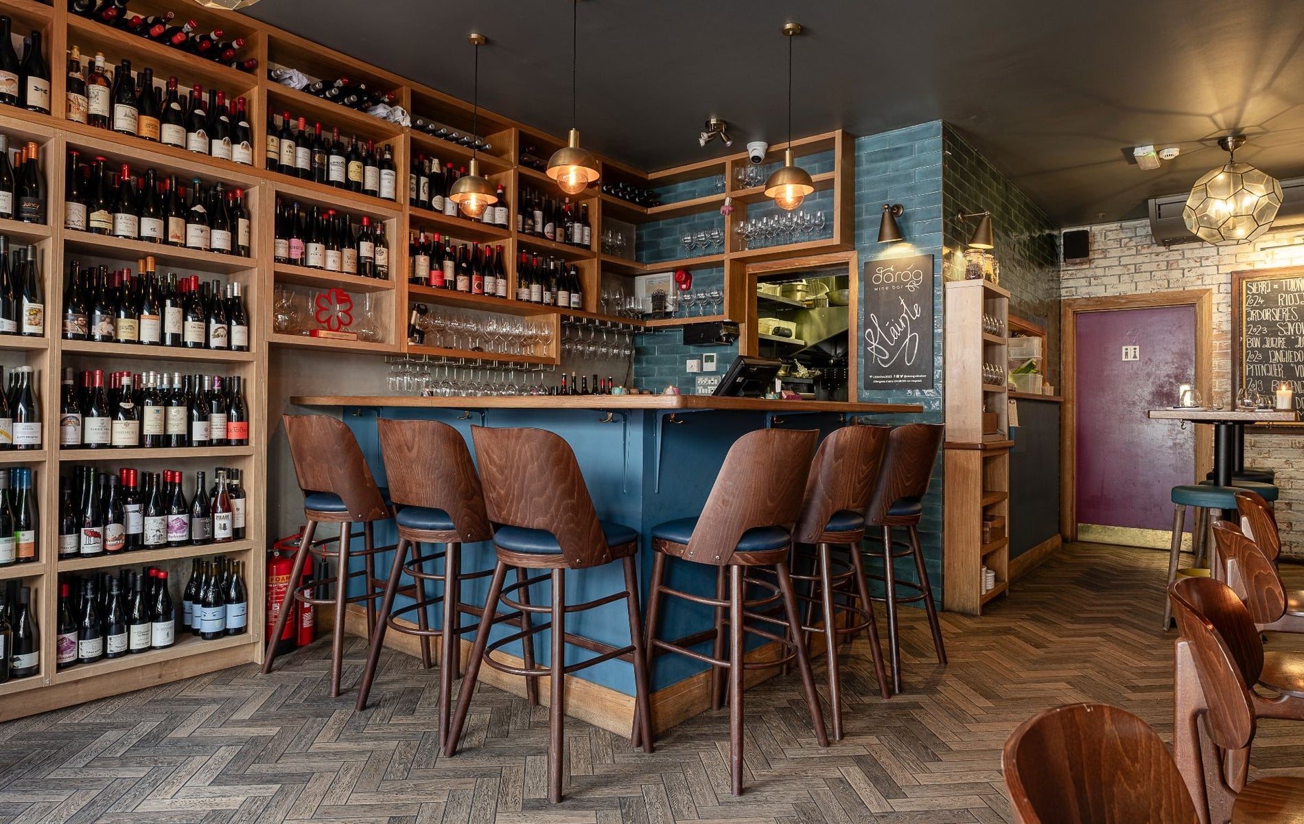A corner bar counter with a floor to ceiling wall of wine bottles