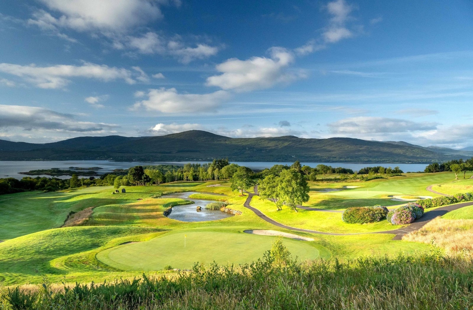 A golf course with a coastal view and mountains in the distance
