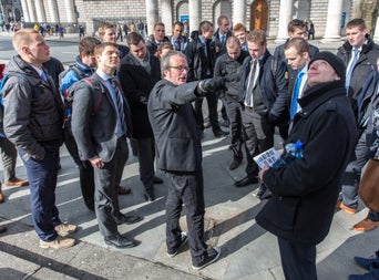 A group of students listening to the stories the tour guide is telling them