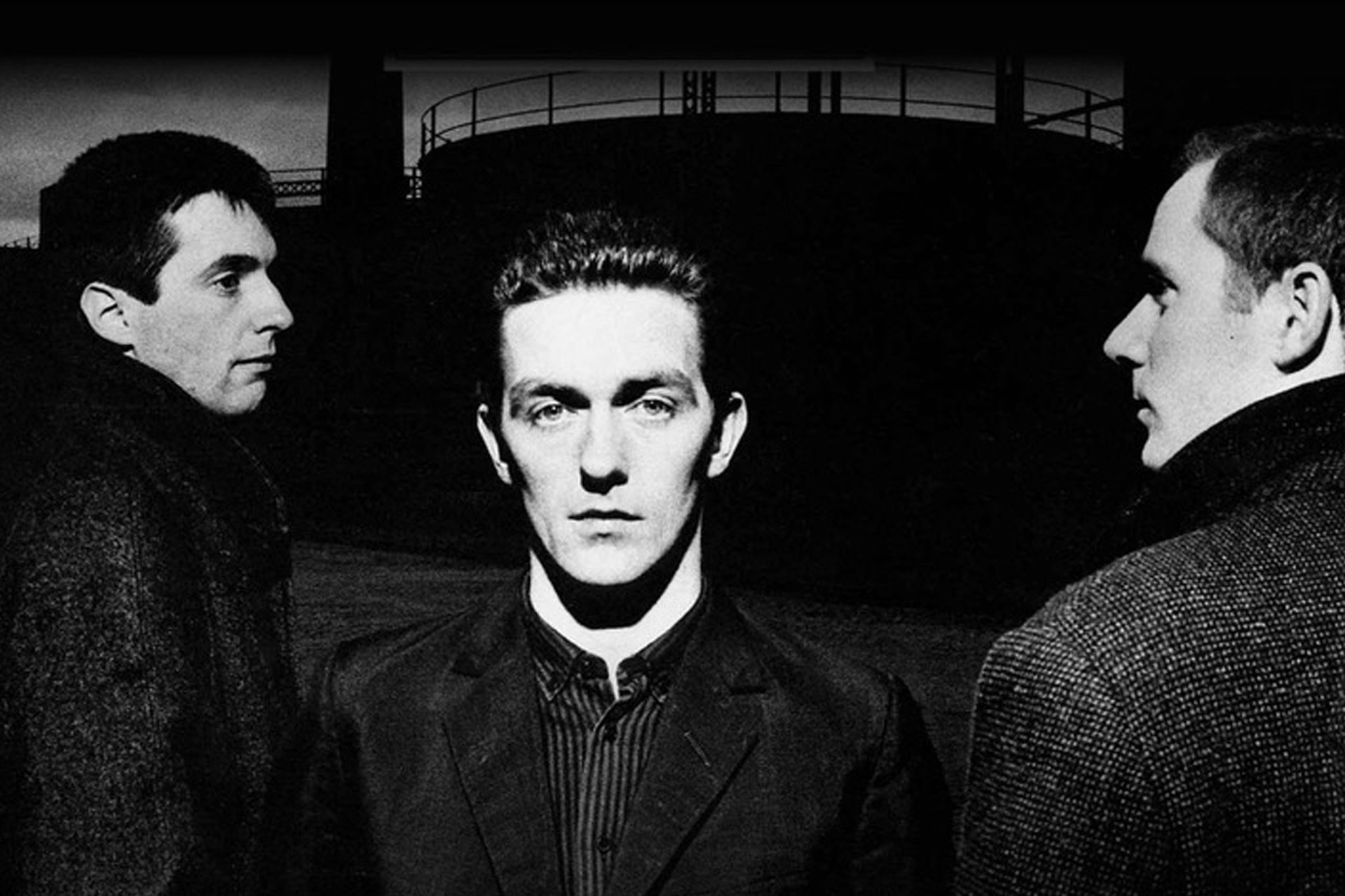 Three serious men in darkly lit photo