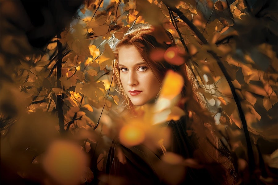 The Cunning Little Vixen, Irish National Opera, the face of a woman viewed through golden and orange autumn leaves