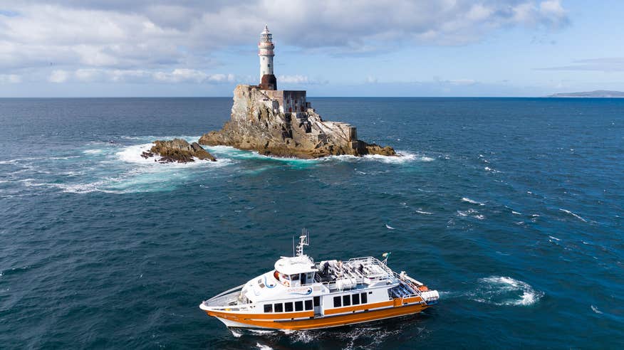 A boat sailing past Fastnet Lighthouse in West Cork