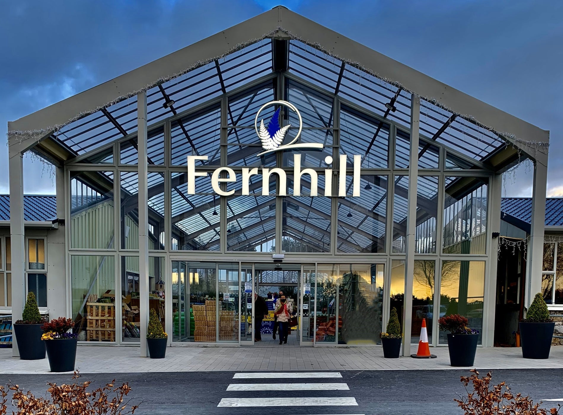 Exterior of a glass garden centre with a road and a pedestrian crossing in front