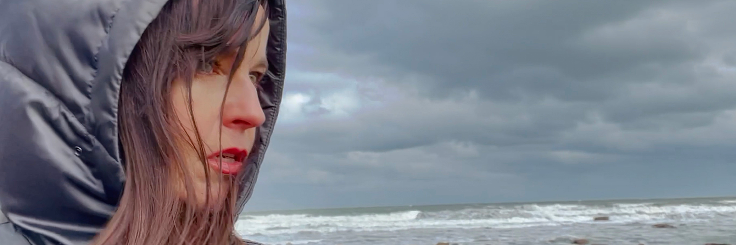 A woman stands in front of a grey sky
