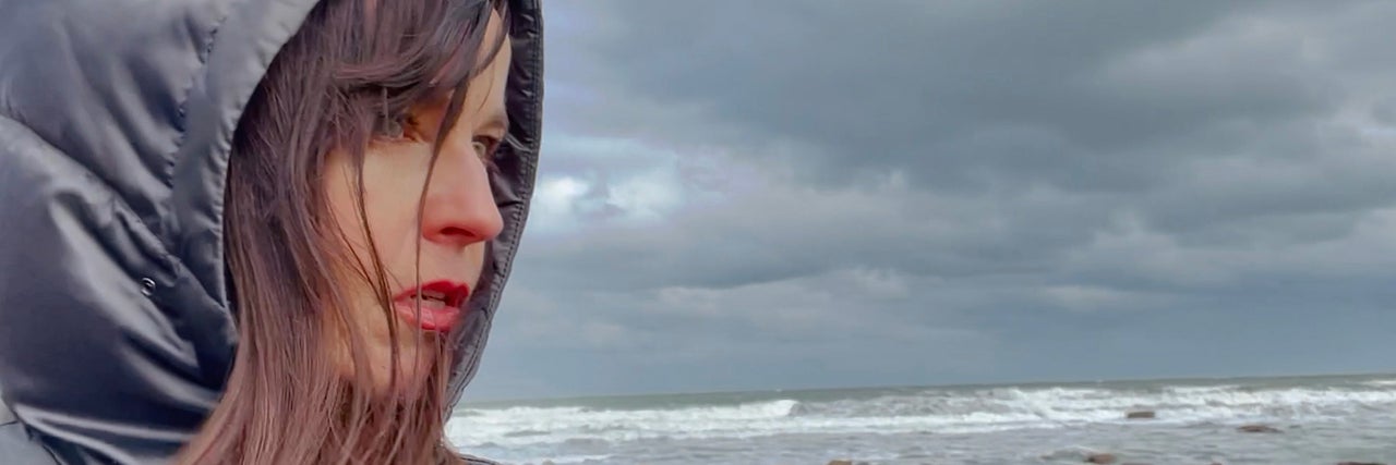 A woman stands in front of a grey sky