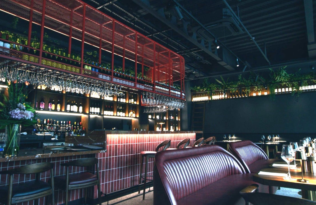 Modern bar area and dark coloured interior of a restaurant with leather seating at tables