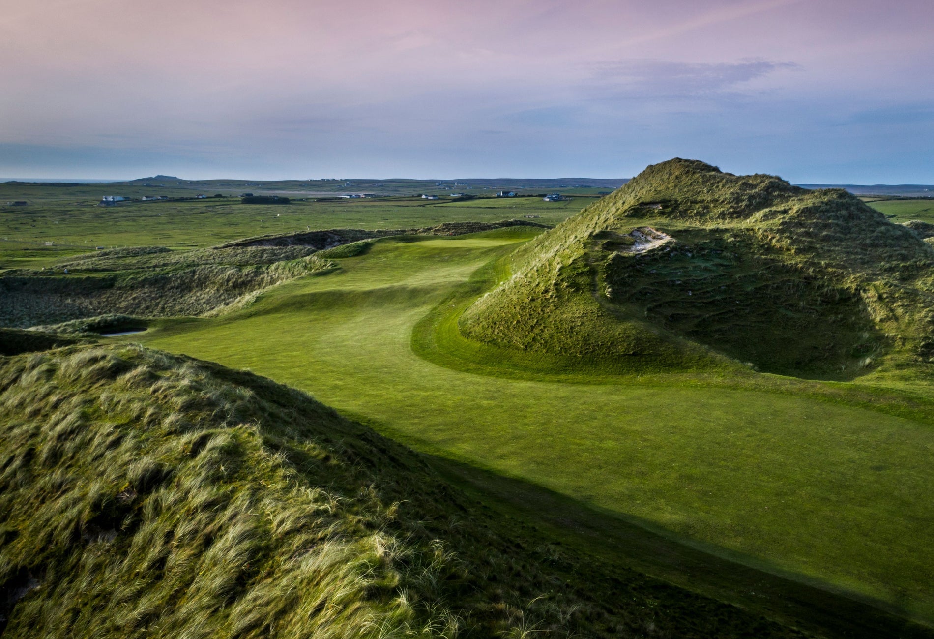 Golf course and bunker with a blue and pink sky in the background