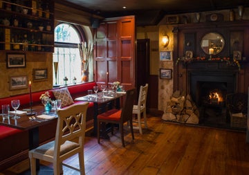 A view of the dining room with a fire in the fire place at Wright's Anglers Rest