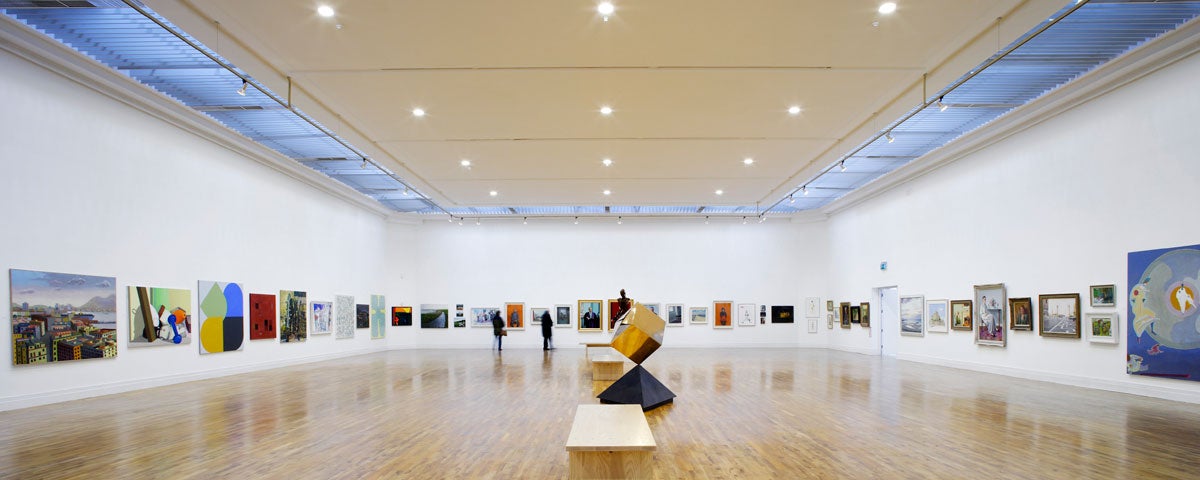 A gallery with artworks on the walls and a sculpture in the centre of the room