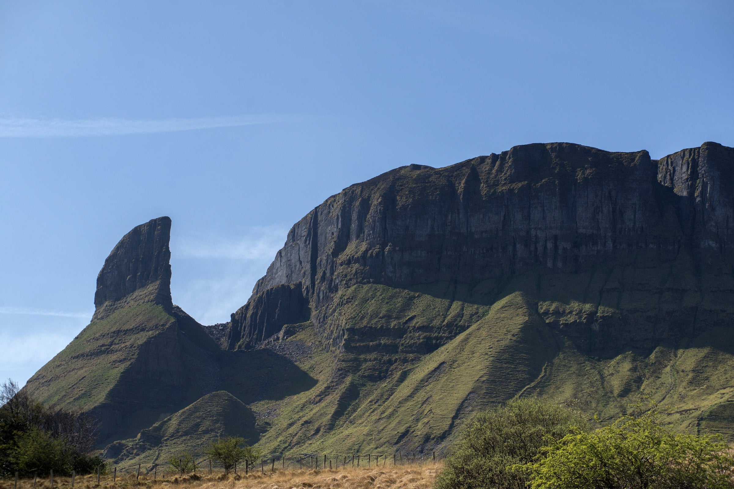 A view of a large rocky tower beside a mountain ridge