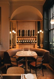 Table and chairs set in front of a domed shelving unit displaying wine