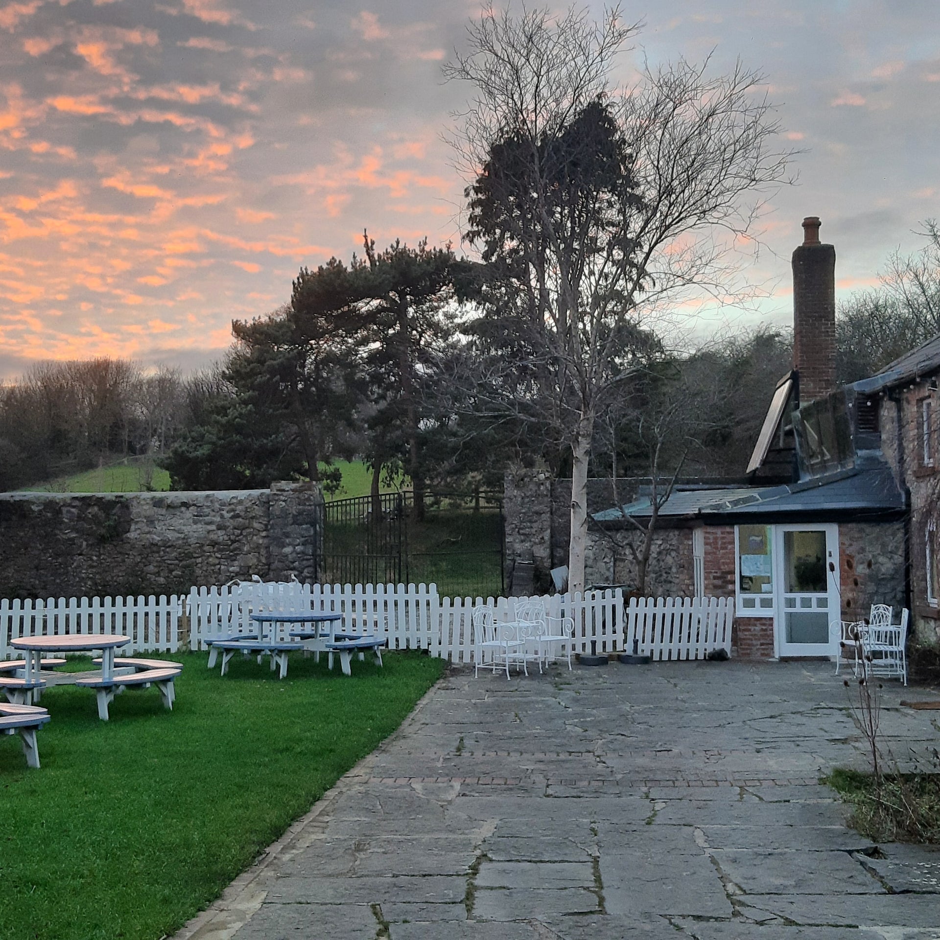 The grounds of a stone building with outside seating