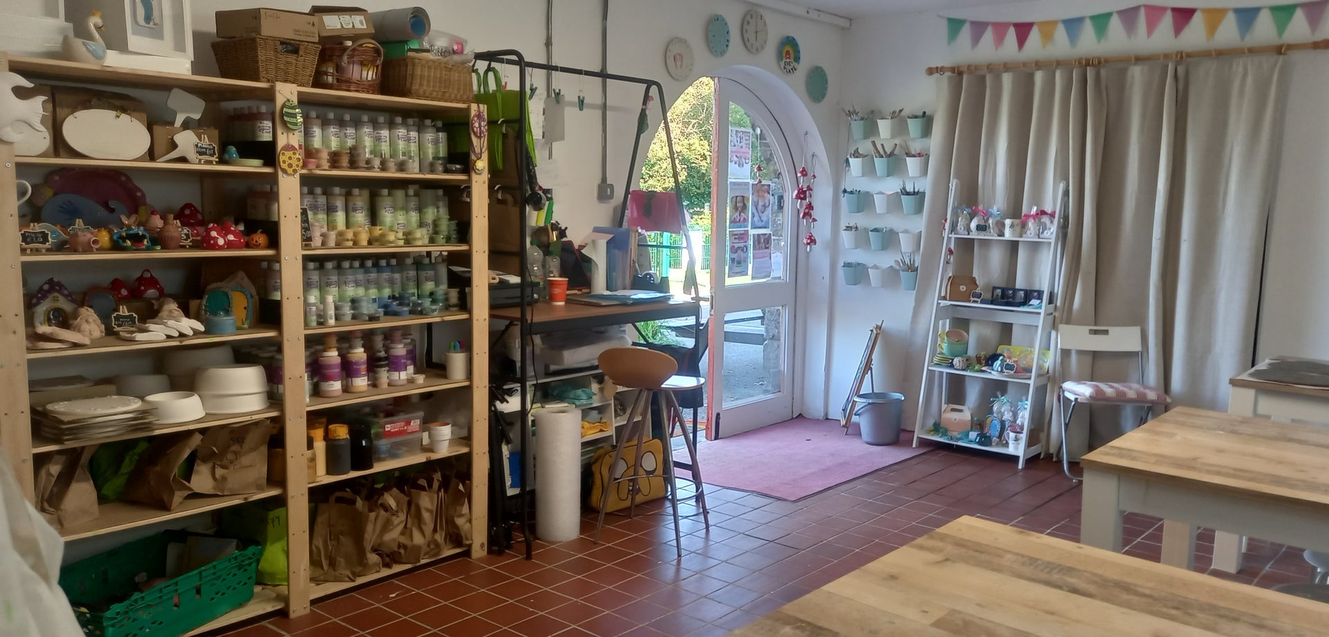 The interior of a decorated pottery studio with shelves of ceramics and benches
