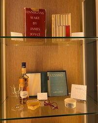 Display shelves containing books, bottle & glass, a pair of glasses and other small items.
