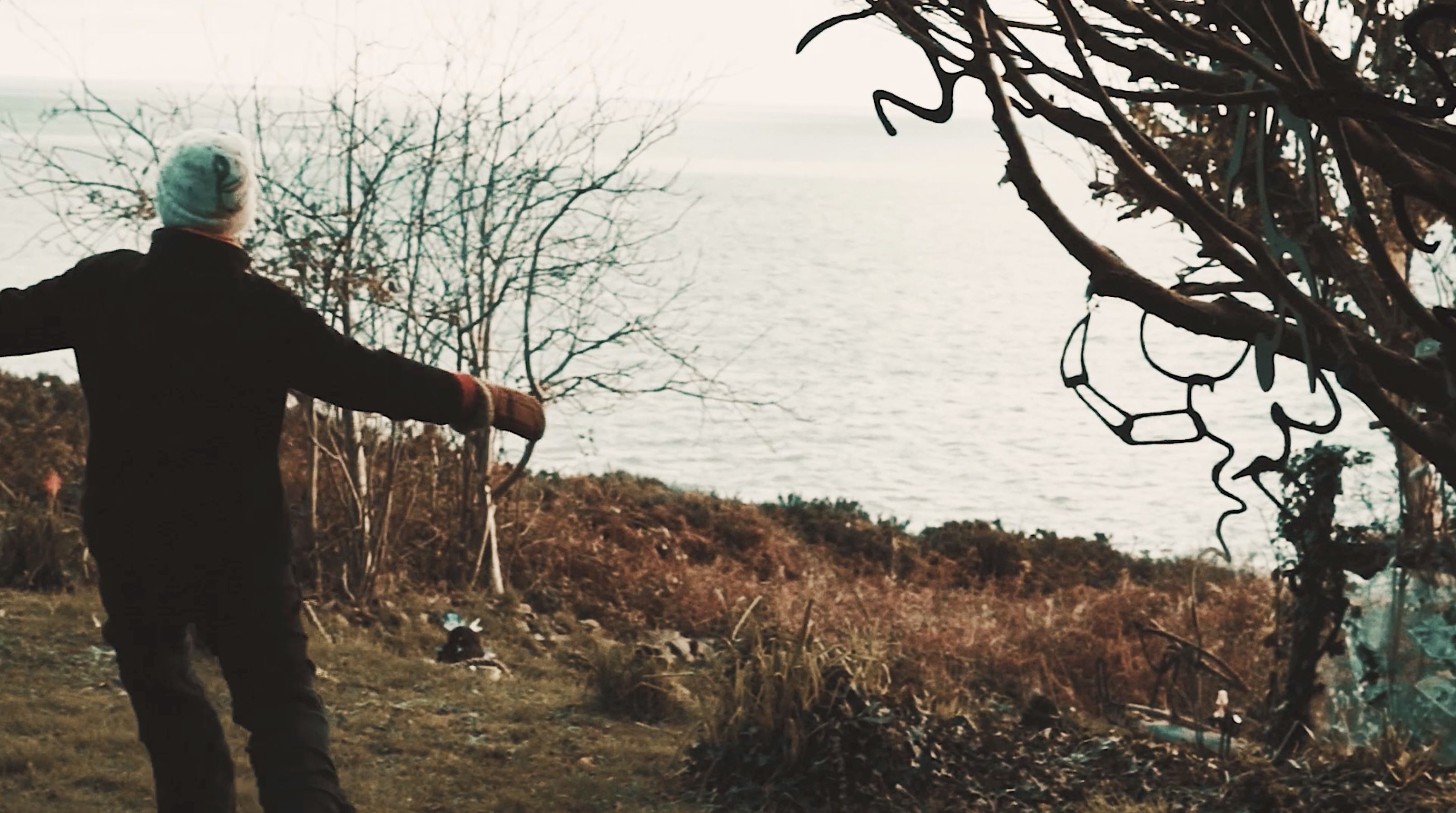 A woman is standing near a large body of water.