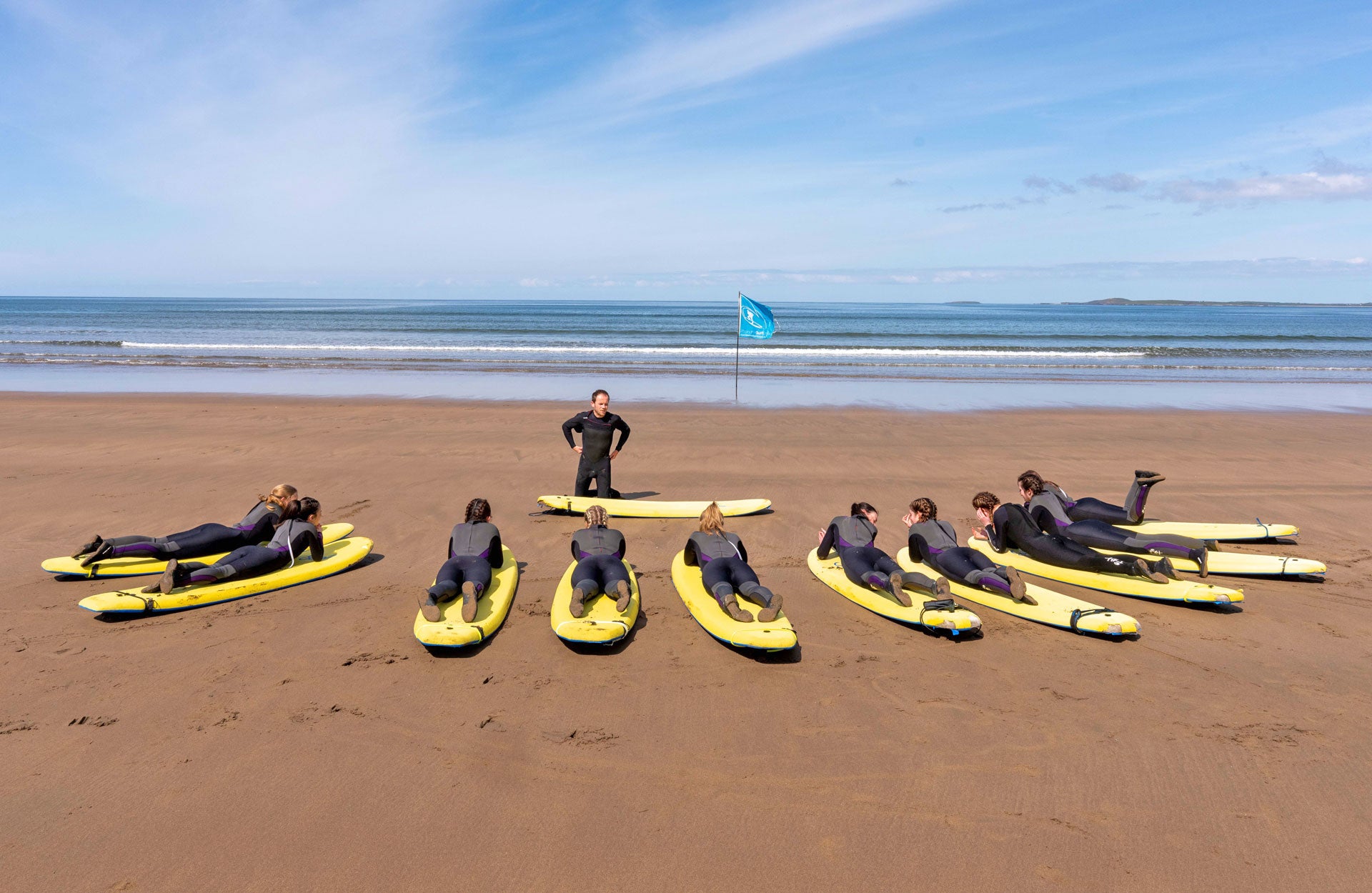 Strandhill Surf School view of ten surfers on boards on the beach with the instructor