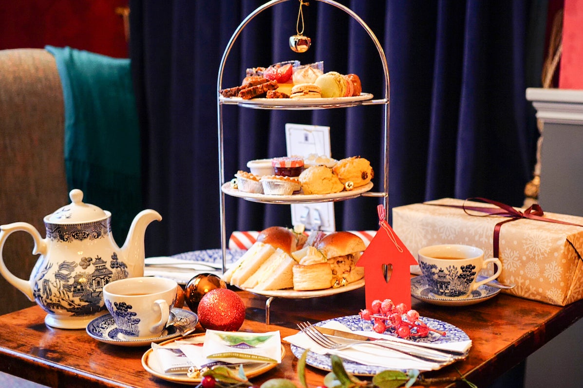 Festive Afternoon Tea stand at Old Music Shop restaurant, the Castle Hotel. Sandwiches, pastries, scone, selection of teas, gifts, Christmas decorations place on a table.