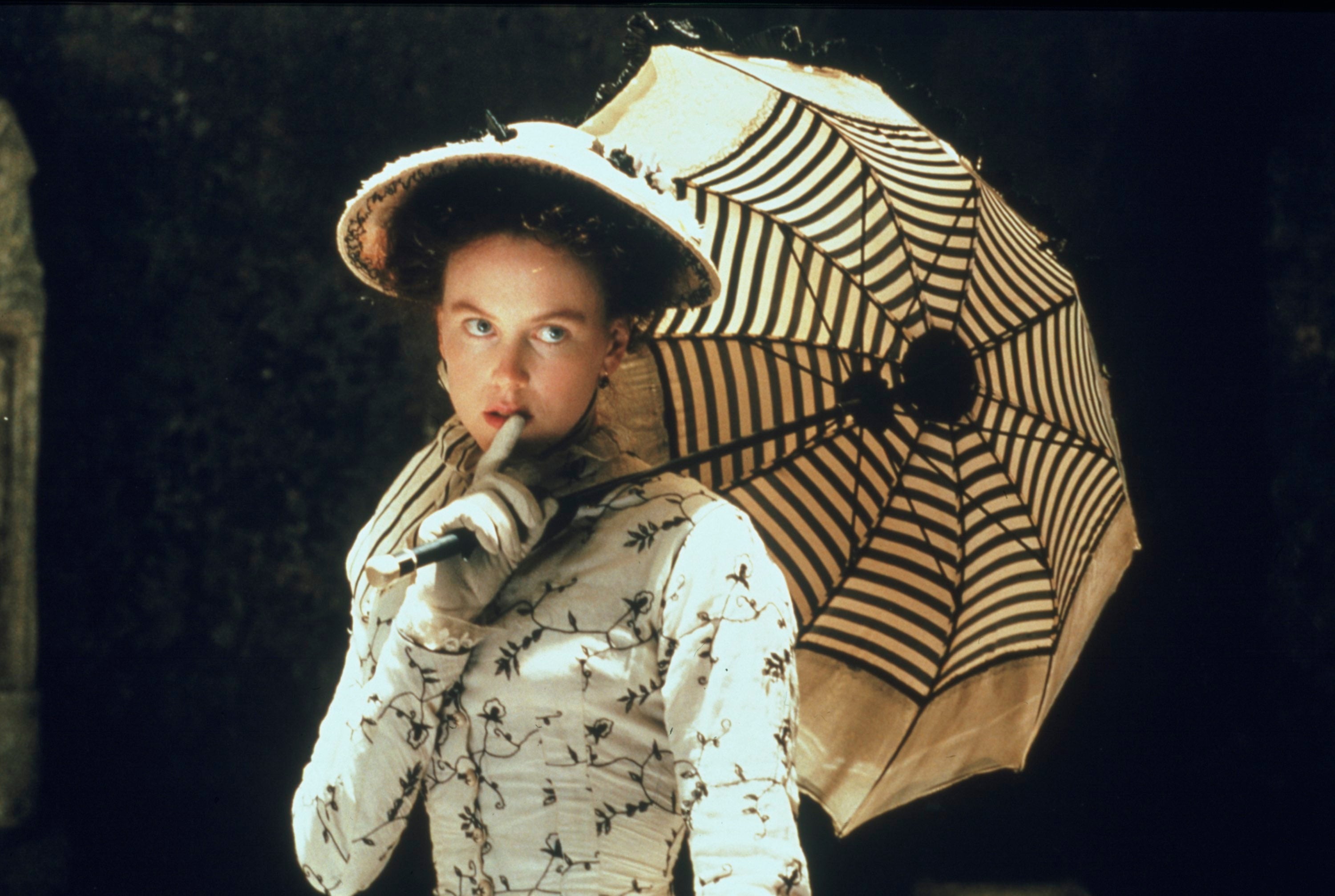 A well-dressed woman with a hat and parasol.