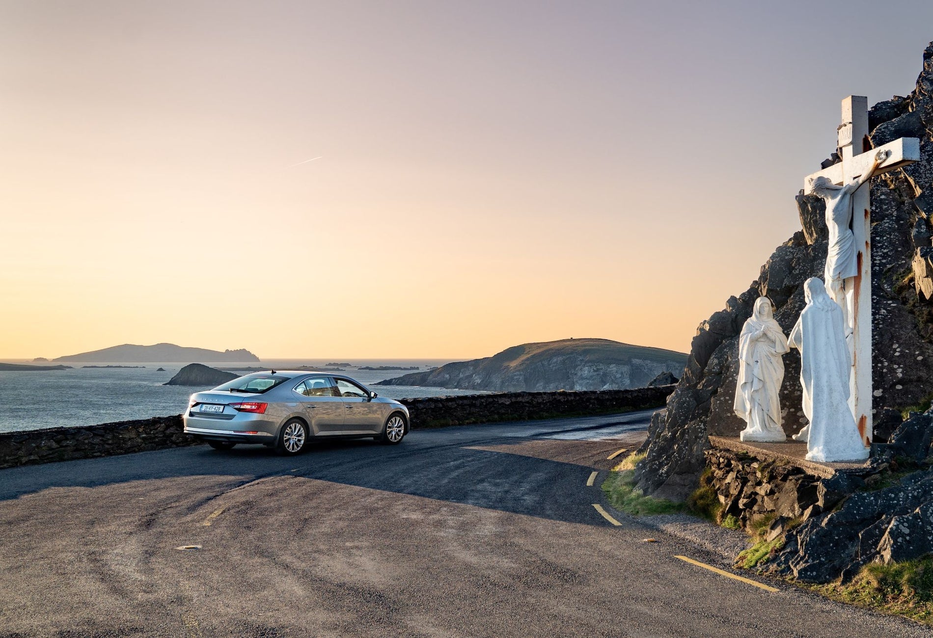 A car parked in front of a grotto depicting the Crucifixion