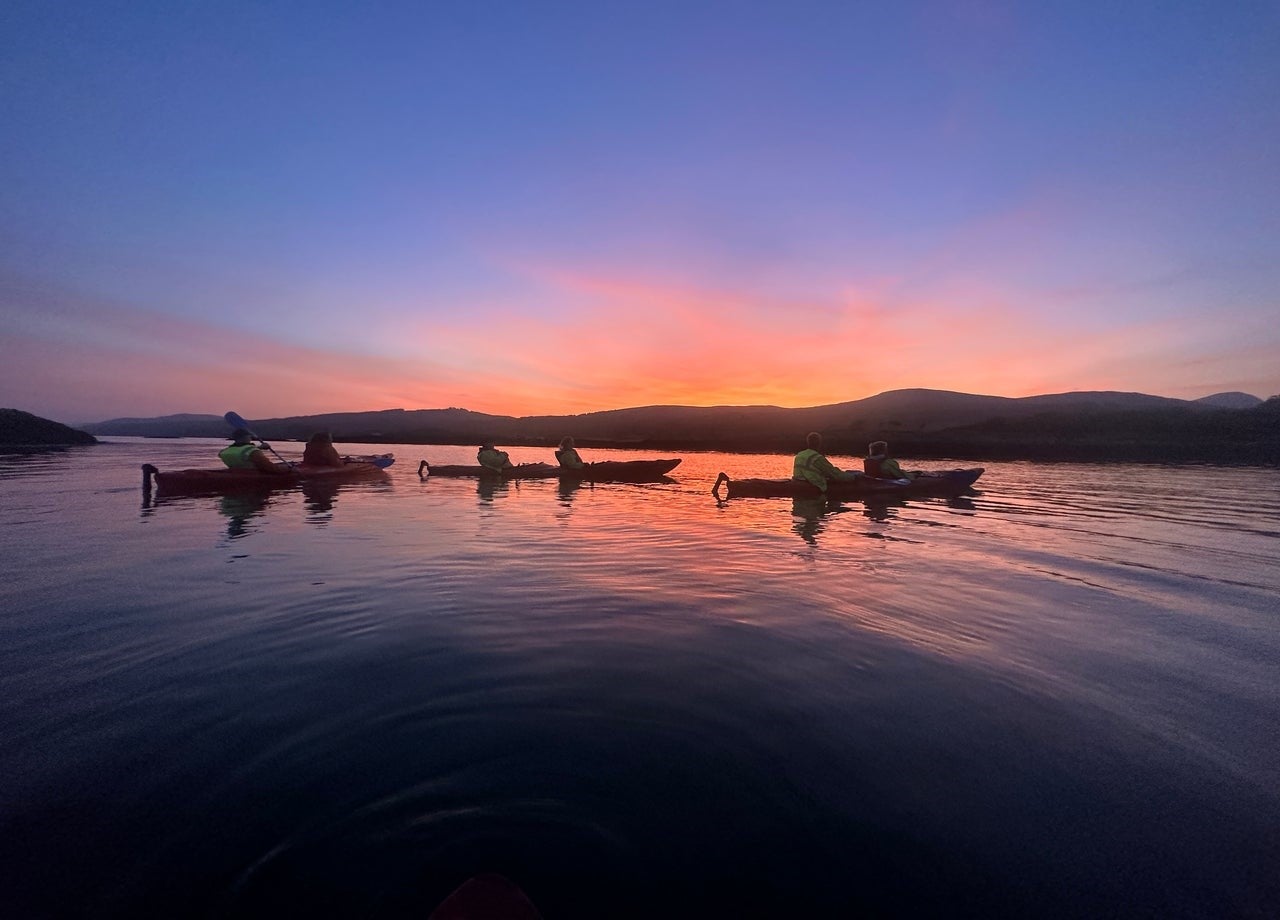 A group of kayakers on Kenmare Bay with a colourful sunset