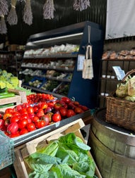 Tomatoes and leafy green vegetables on display in a farm shop
