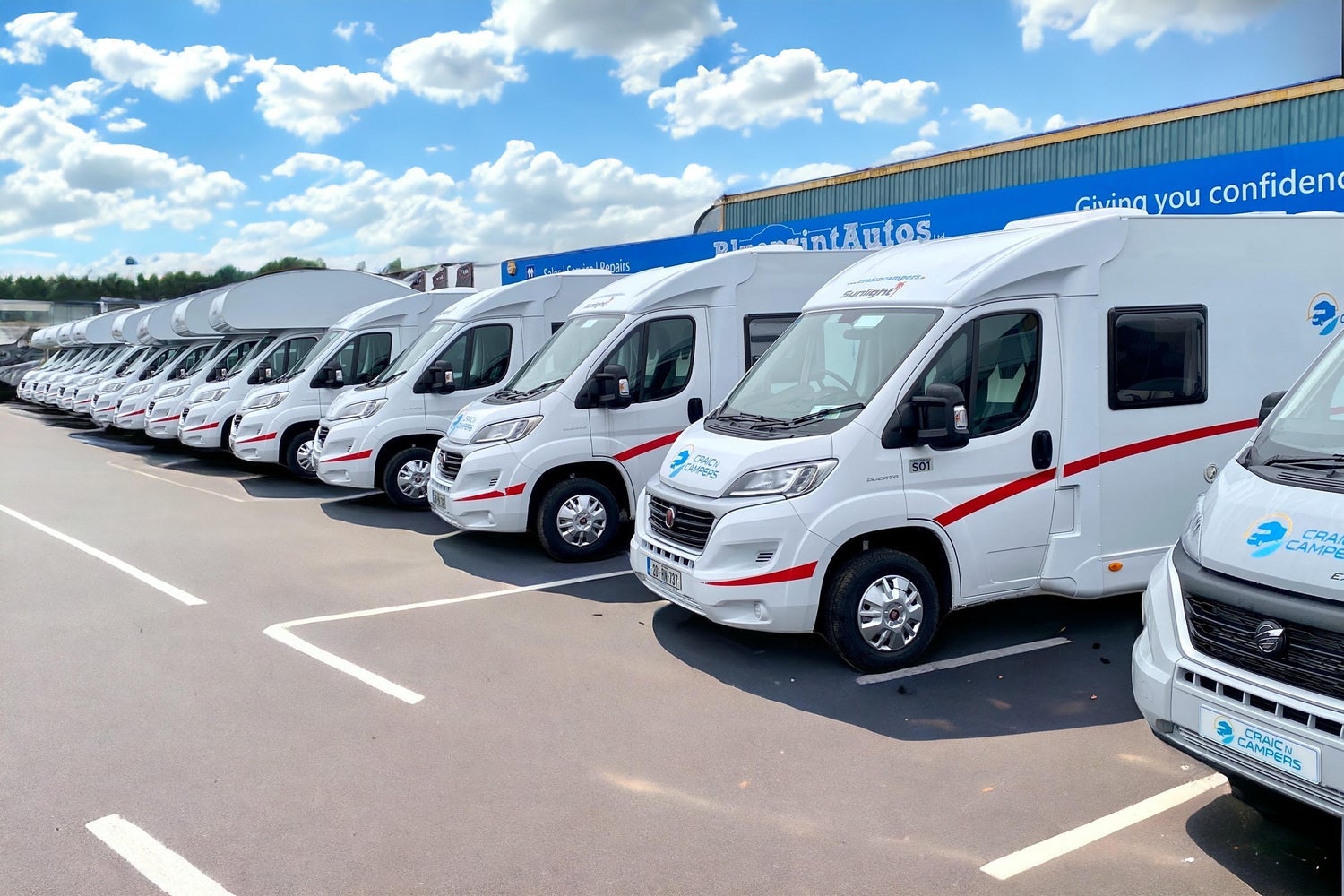 Row of campervans parked outside a rental agency building