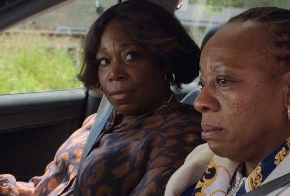 2 serious looking women are seated in a car.