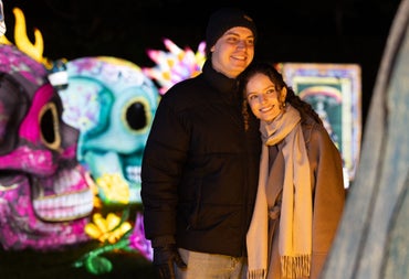 Two visitors posing among brightly lit skeleton lantern sculptures at Dublin Zoo Wild Lights