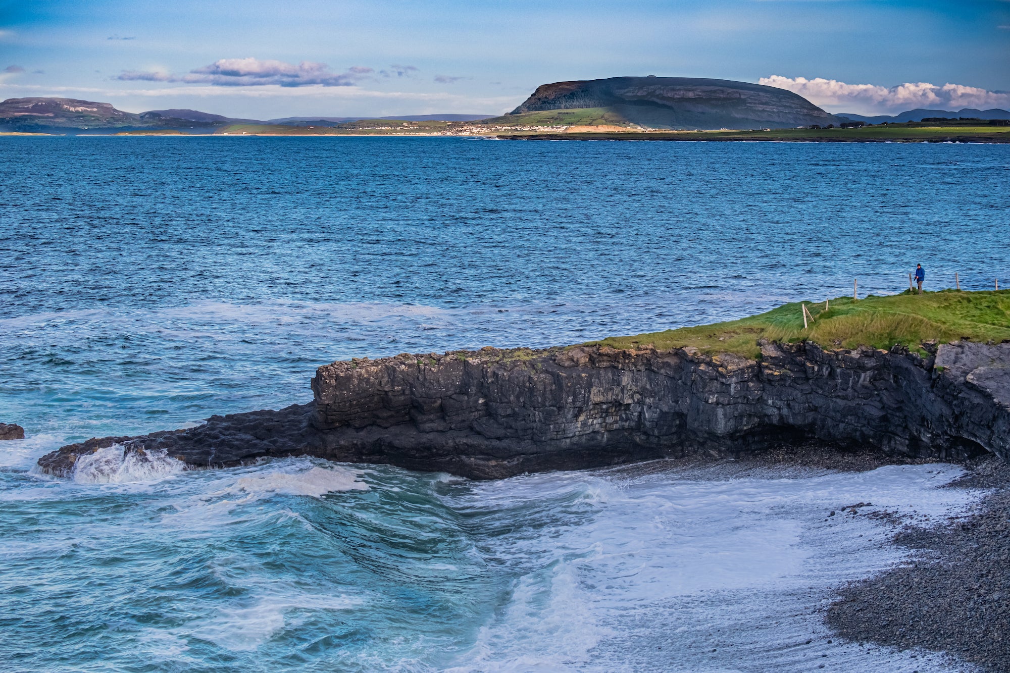 A person standing on Aughris Head, Sligo with a mountain in the background.