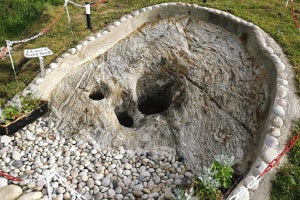 Image of a holy well surrounded by stones and grass.