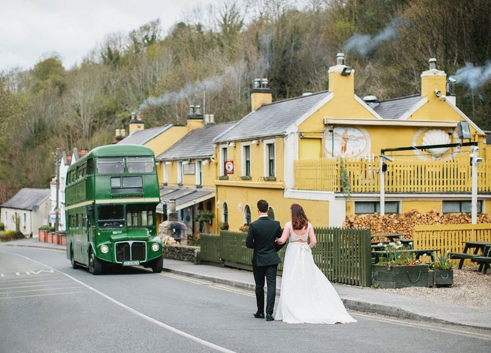 Bride and groom walking towards Wright's Anglers Rest where a green double decker bus is parked outside