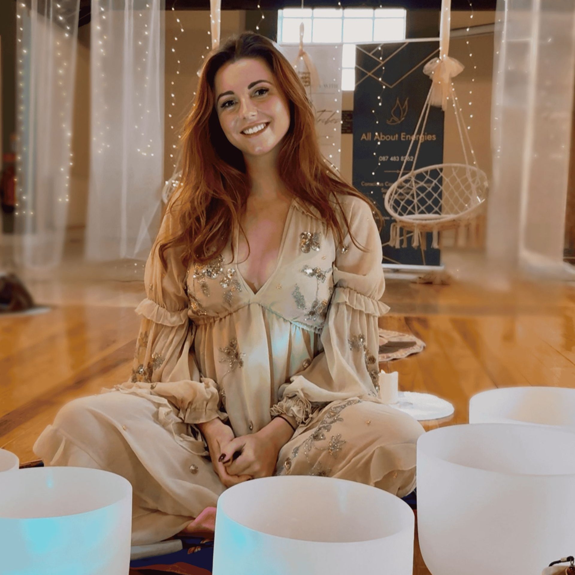 A lady sitting by crystal singing bowls at All About Energies