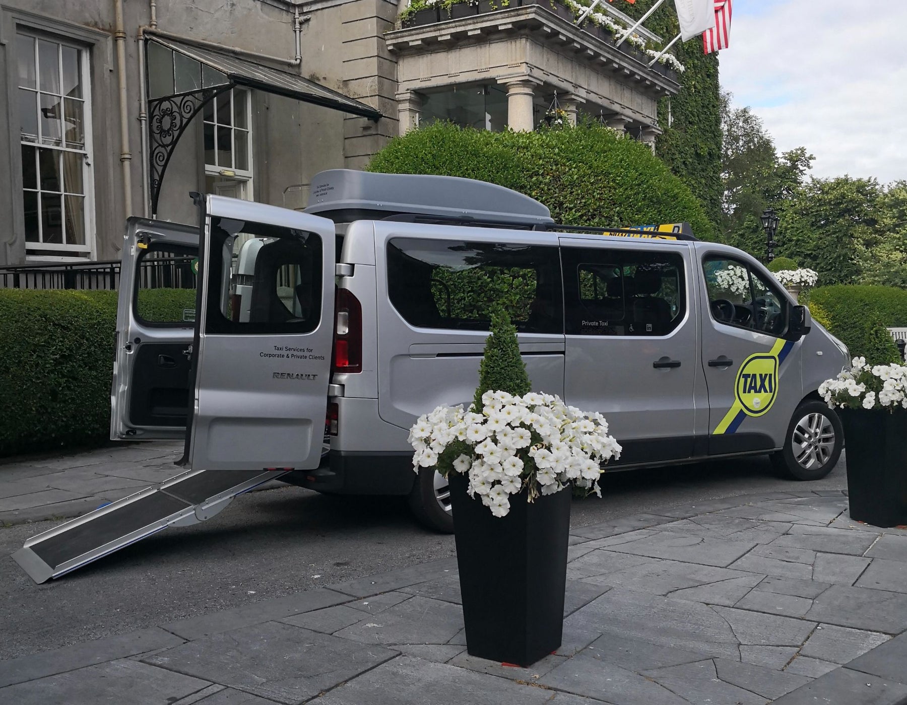 A wheelchair accessible taxi parked outside a hotel with Dublin Wheelchair Taxis