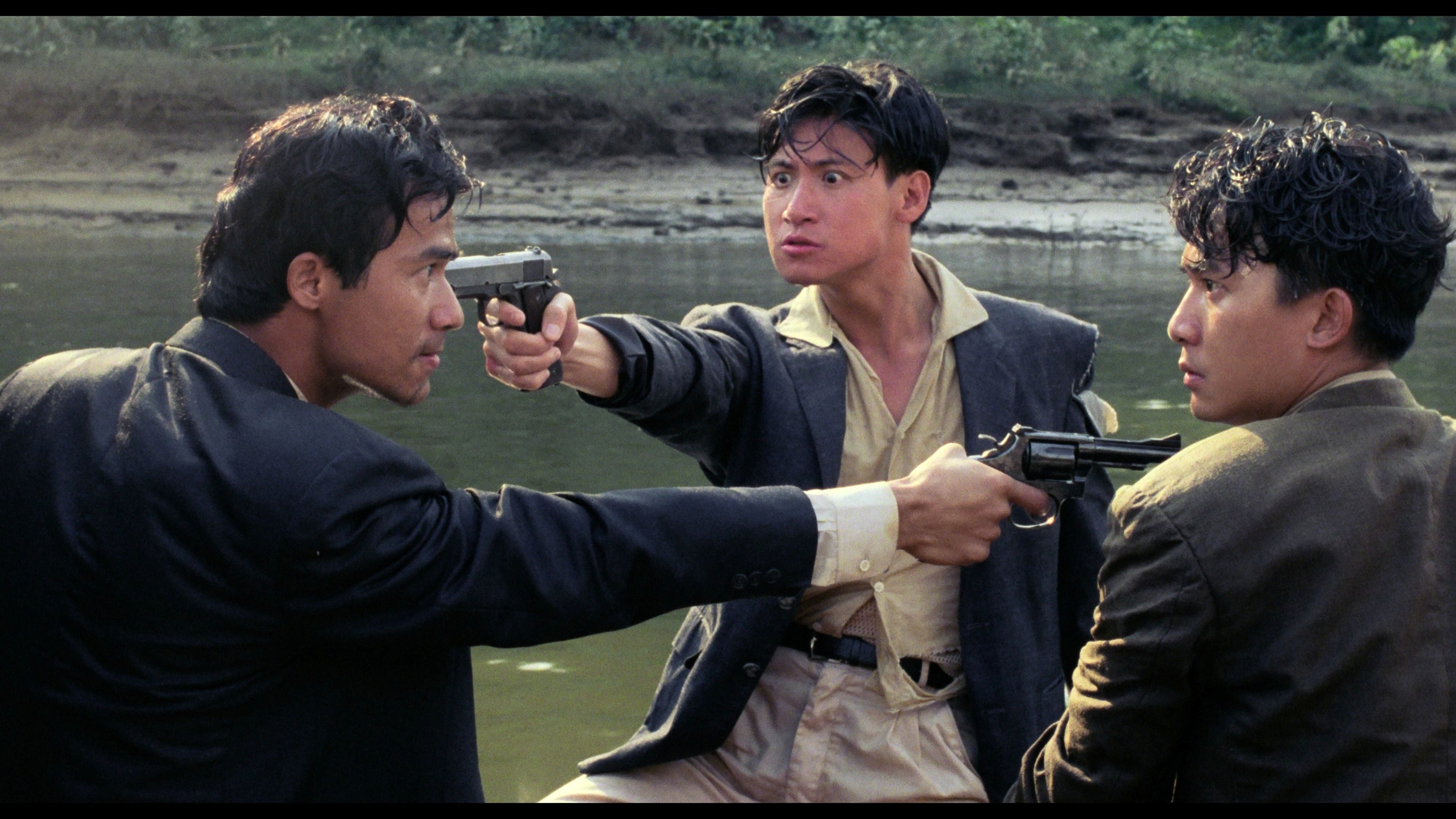 A man pointing a pistol at a man who is pointing a pistol at a third man.